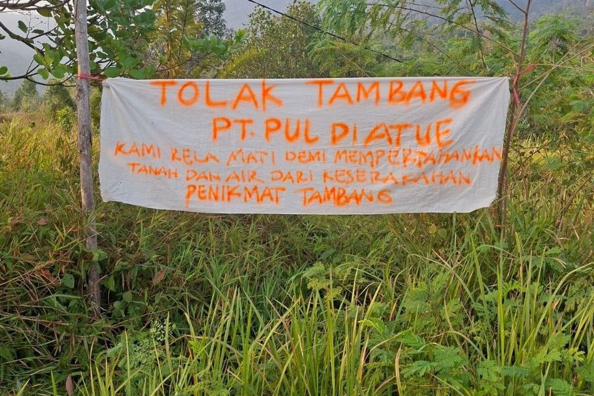 Spanduk TOLAK TAMBANG PT PUL DI ATUE dipasang warga di tepi lahan berstatus HPL transmigrasi lokal